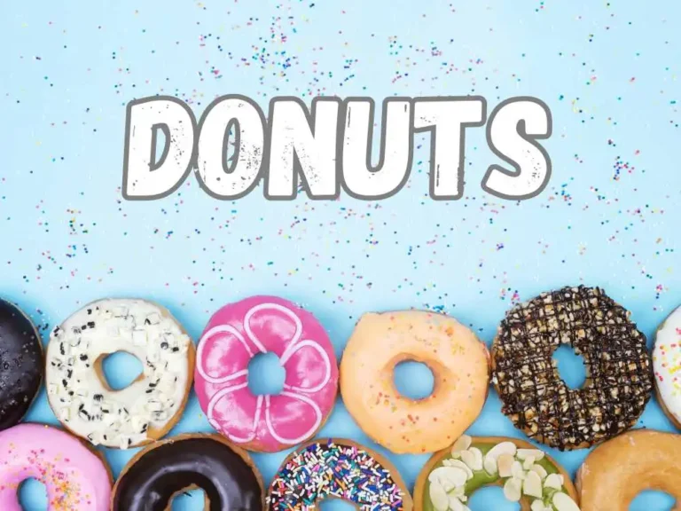 Lindos donuts confeitados e arrumados em sequencia em cima de uma mesa.