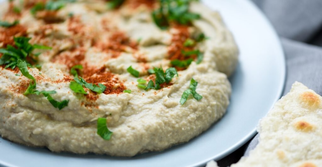 Babaganoush cremoso da culinária árabe servido com azeite e pão sírio.