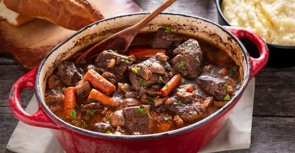 Boeuf Bourguignon servido com legumes rústicos e molho espesso de vinho tinto, prato clássico da culinária francesa.