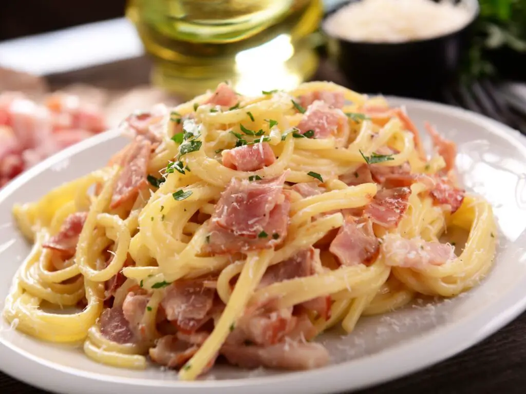 Prato de espaguete à carbonara, coberto com molho cremoso de ovos e queijo, bacon crocante e pimenta-do-reino moída.