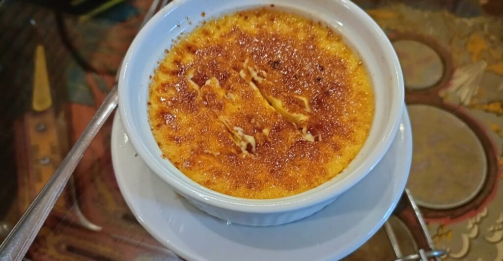 Crème brûlée com crosta caramelizada dourada, servido em ramequim, sobremesa clássica da culinária francesa.