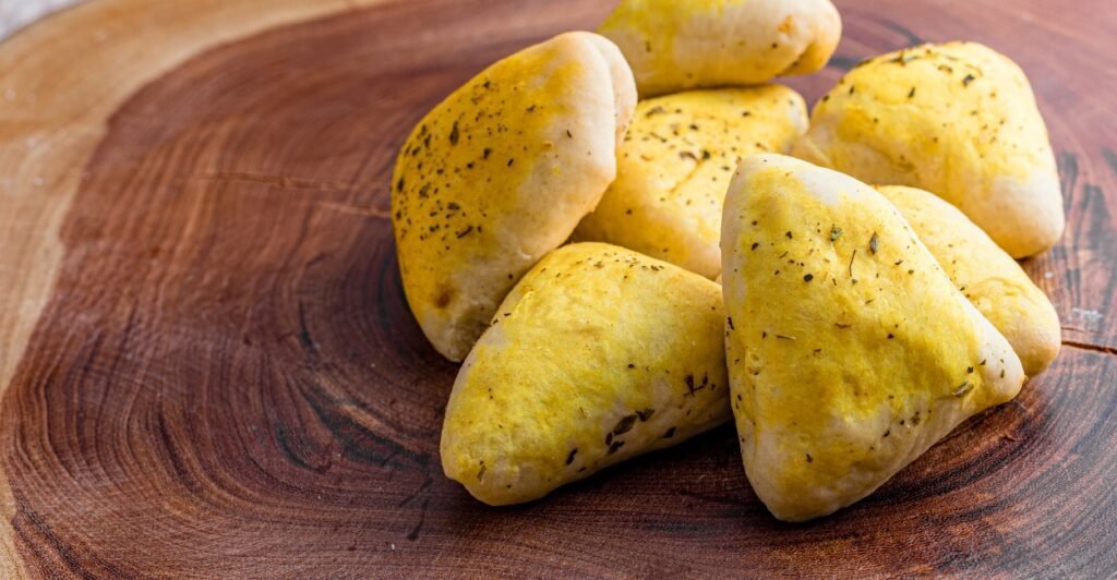 Fatayer da culinária árabe com recheio de espinafre e massa dourada em formato triangular.