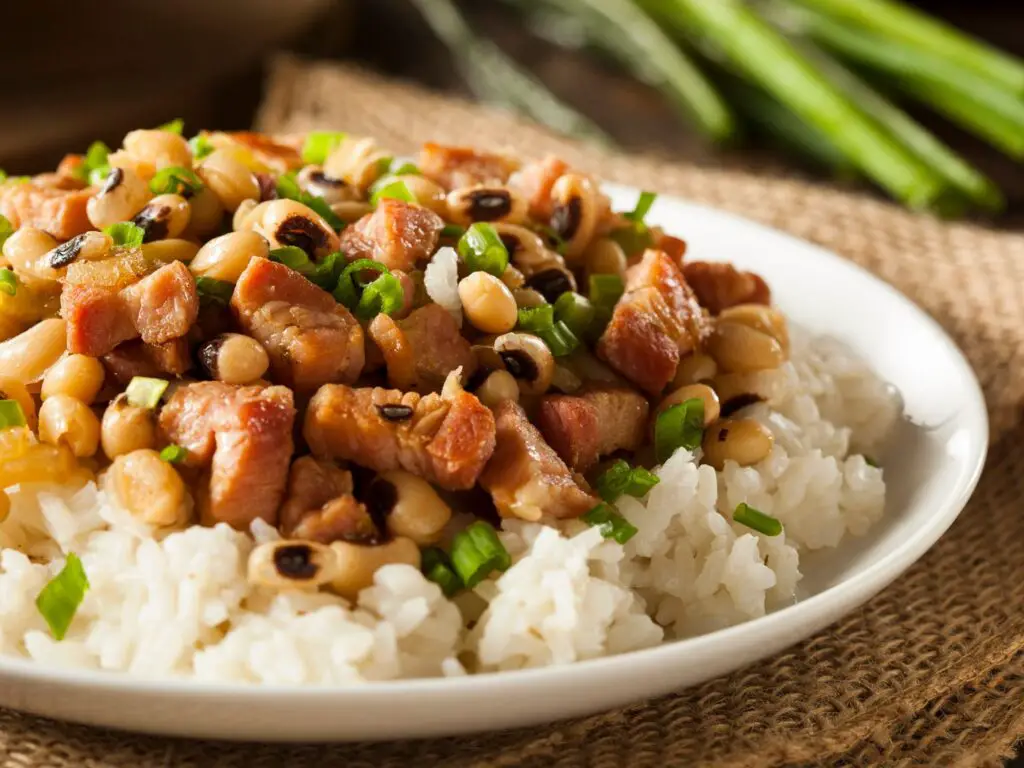 Prato de Hoppin' John servido em um prato  composto por arroz branco, feijão-fradinho e pedaços de bacon.