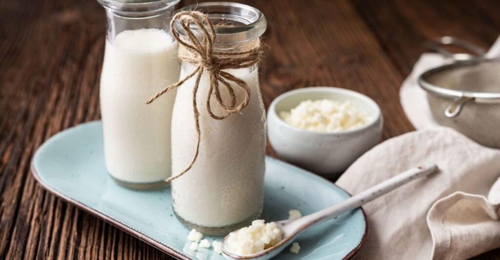 Copo de kefir branco sobre mesa de madeira.