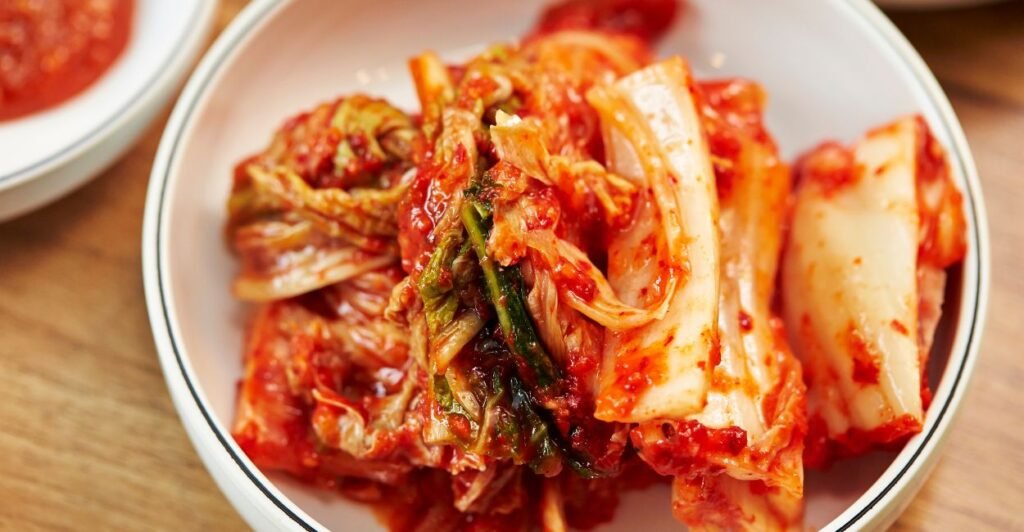 Porção de kimchi coreano em prato de cerâmica. Acelga fermentada ao estilo coreano com pimenta vermelha, alho e gengibre.