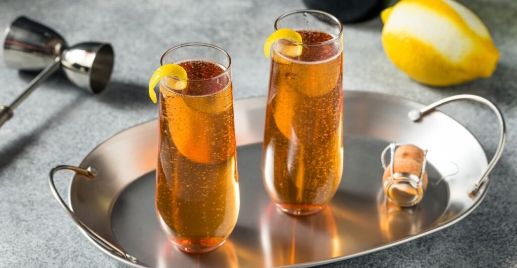 Taça de Kir francês com vinho branco e cassis. Coquetel elegante servido em taça alta, com leve tom rosado e fatia de limão.