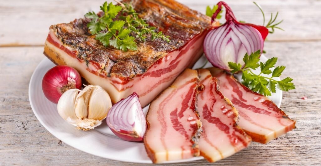 Fatias finas de Lardo di Colonnata, toucinho curado tradicional italiano, dispostas em prato.