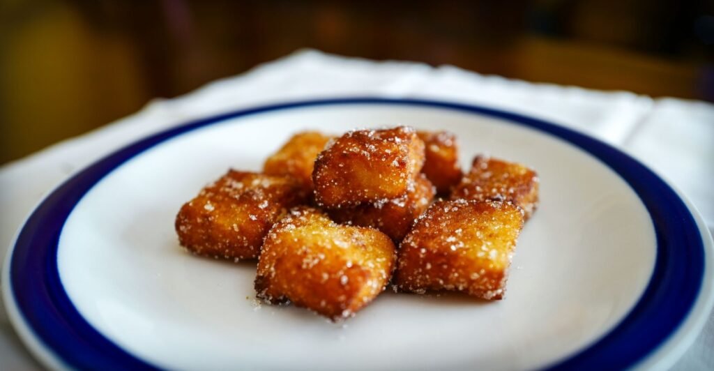 Porção de Leche Frita dourada, doce espanhol crocante por fora e macio por dentro, servida com açúcar polvilhado.