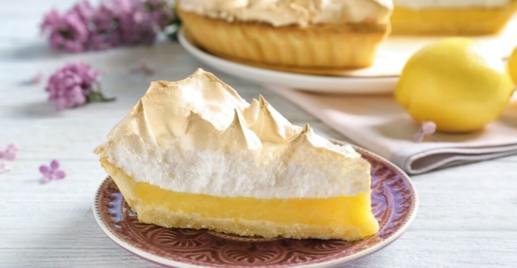 Fatia de lemon pie com massa crocante, recheio cremoso de limão e cobertura de merengue dourado.