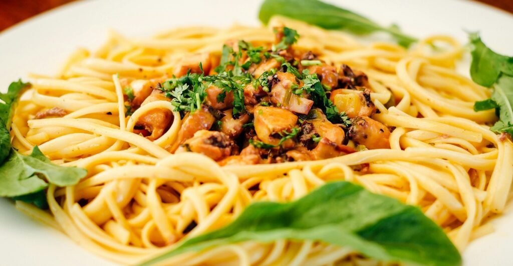 Prato de linguine ao alho e óleo com ervas frescas e pedaços dourados de alho.