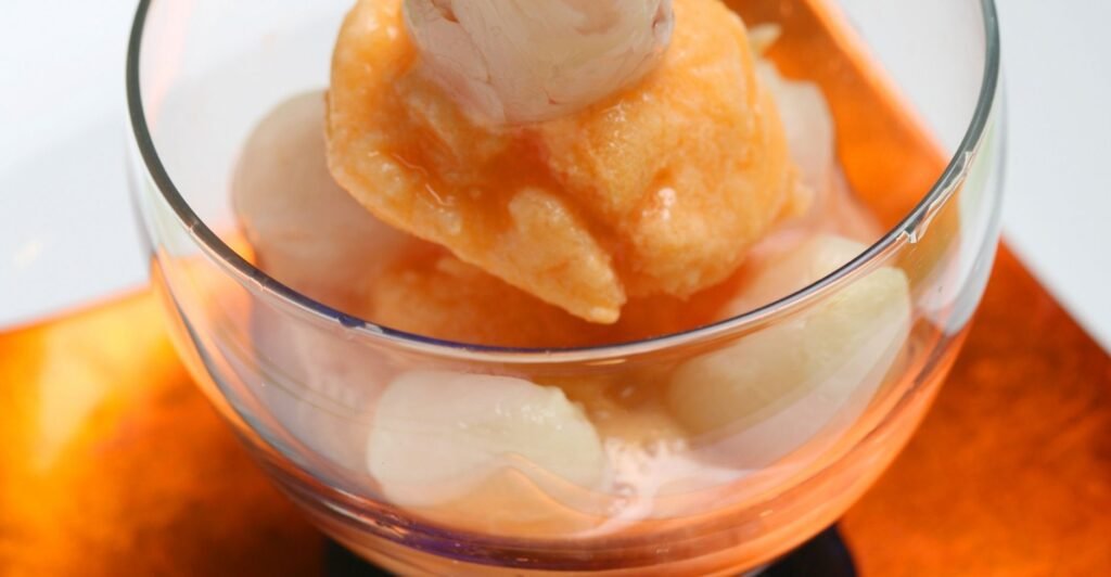 Taça de sorvete de lichia cremoso e gelado, decorado com frutas frescas.