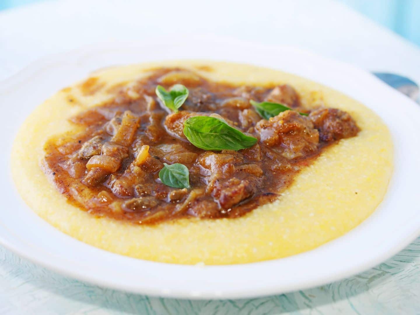 Polenta cremosa coberta com molho de carne, servida em um prato.