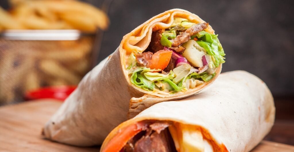 Shawarma árabe enrolado em pão sírio, recheado com carne, salada e molho.