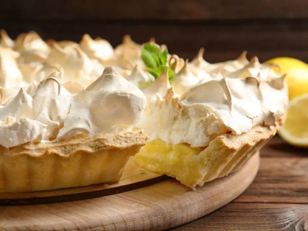 Torta de limão coberta com merengue, com uma crosta dourada e uma camada de merengue dourado e espumoso no topo.