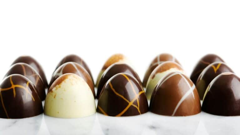 Trufas gourmet em uma bandeja elegante, com revestimento de cacau em pó, chocolate granulado e confeitos.