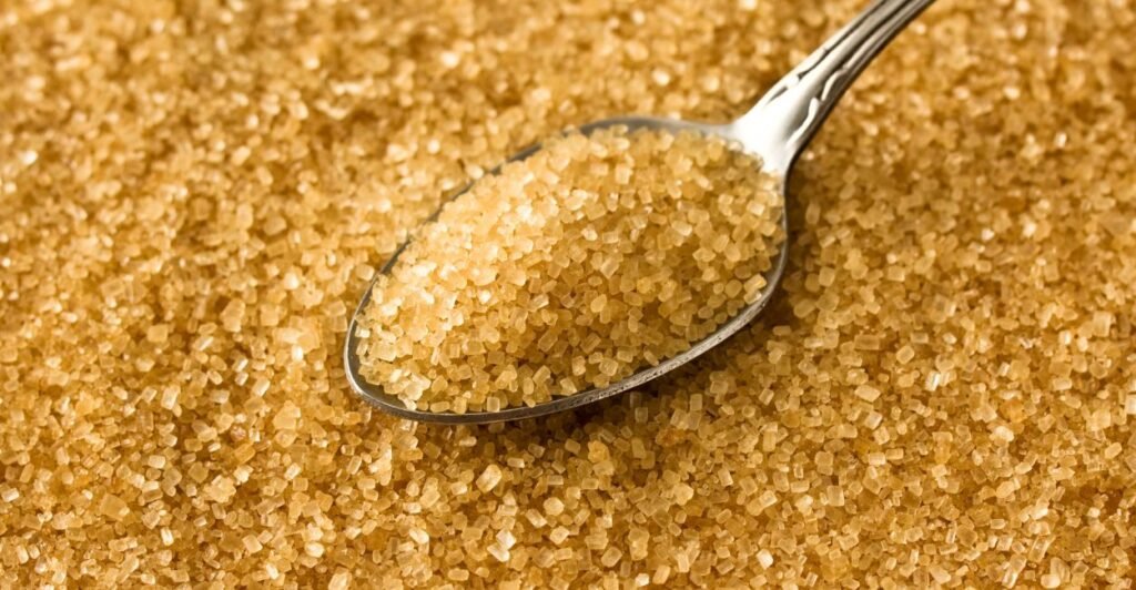 Cristais de açúcar demerara de cor marrom-claro e granulometria grande preenchendo uma tigela.