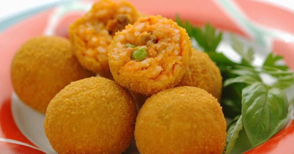 Prato de arancini: Bolinhos de arroz dourados e crocantes, servidos com uma deliciosa molho marinara. Uma explosão de sabores italianos em cada mordida!