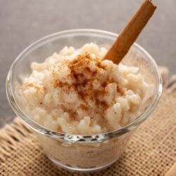 Arroz doce cremoso em tigela branca com canela polvilhada por cima,