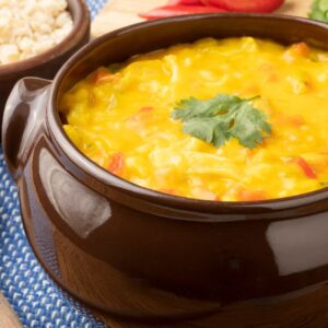 Bobó de camarão cremoso servido em panela de barro com arroz branco ao lado.