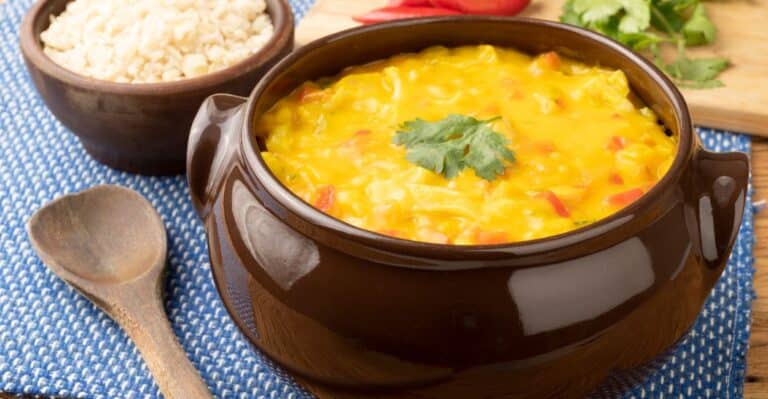 Bobó de camarão cremoso servido em panela de barro com arroz branco ao lado.