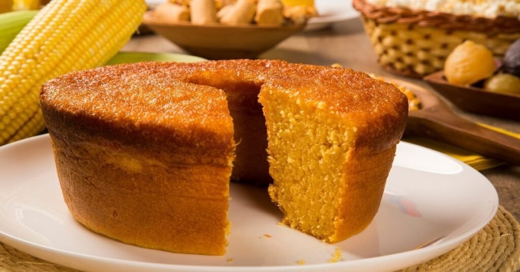 Bolo de milho dourado fatiado em prato rústico, tradicional comida de festa junina doce.