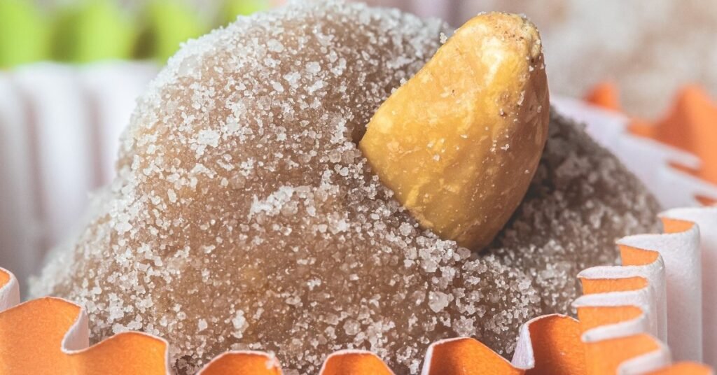 Cajuzinhos decorados com amendoim inteiro no topo, servidos em forminhas coloridas, comida de festa junina doce.