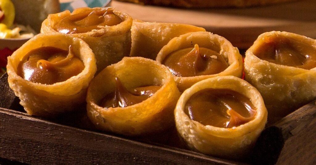 Canudinhos crocantes recheados com doce de leite cremoso, alinhados sobre bandeja típica, comida de festa junina doce.