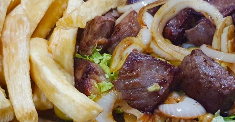 Carne de sol com macaxeira servida em prato rústico com manteiga de garrafa, cebola e cheiro-verde.