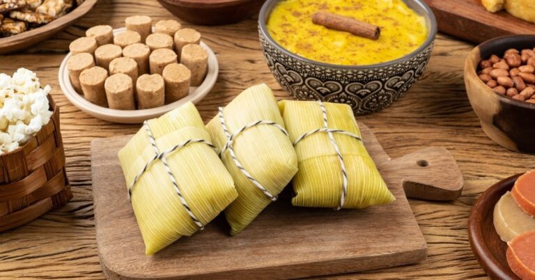 mesa com comida de festa junina doce. opçoes como pamonha, paçoca, curau e muitos outros.