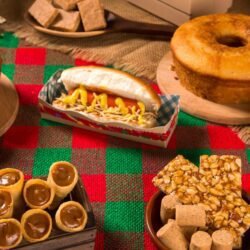 Mesa decorada com diversas comidas típicas de festa junina como canjica, pamonha, bolo de fubá, milho cozido e pé de moleque