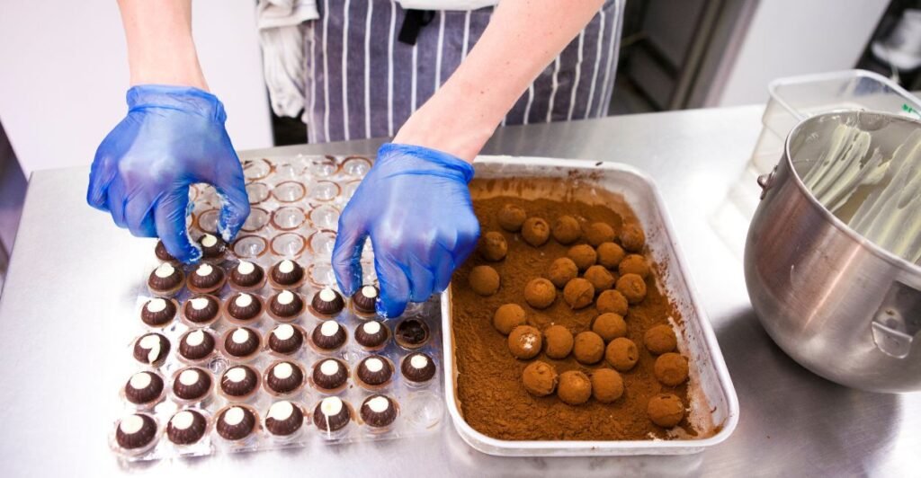 confeiteira ensinando como fazer trufas de chocolate, utilizando uma forma para fazer as trufas.