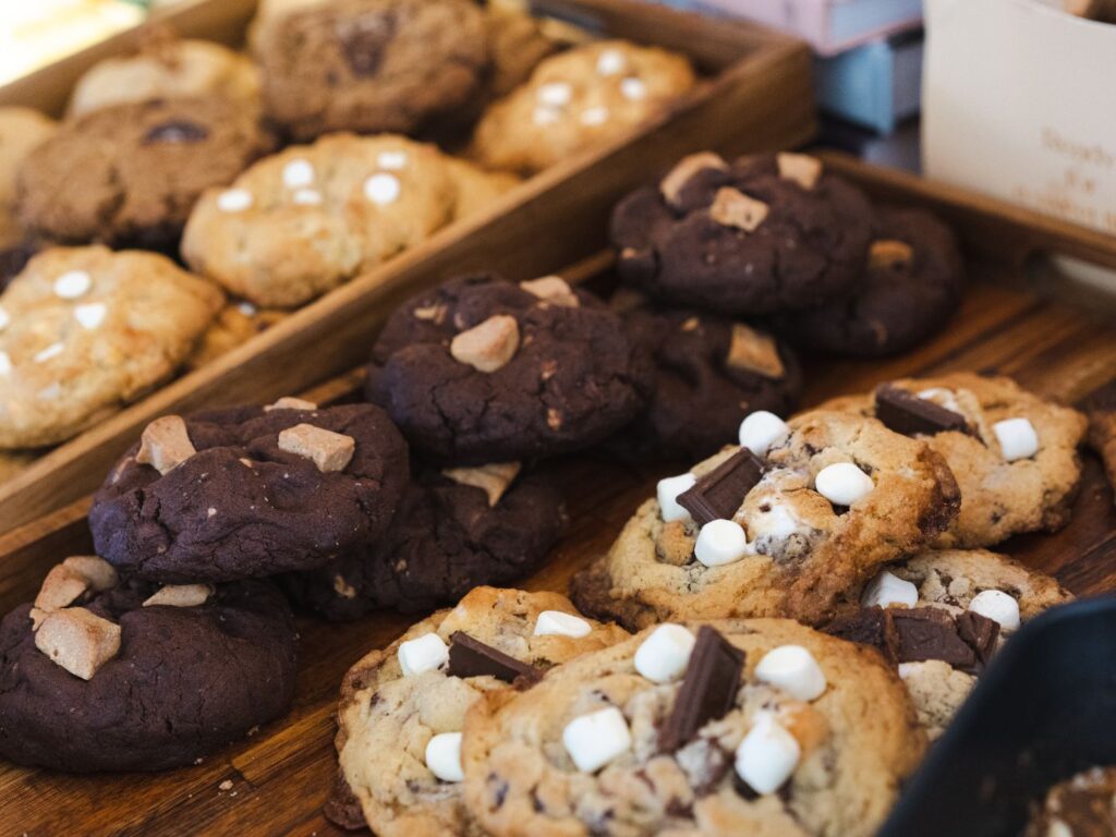 Cookies artesanais com pedaços de chocolate, dispostos em uma bandeja rústica, prontos para venda.