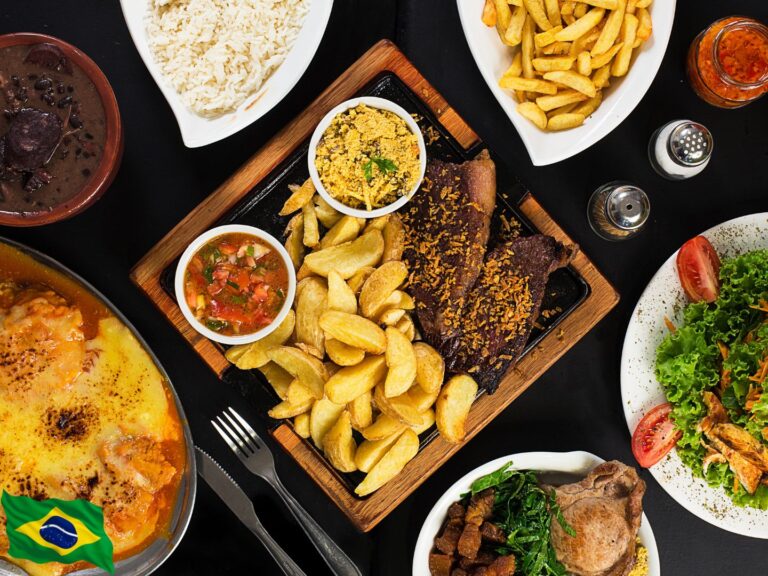 Churrasco de picanha da culinária brasileira, acompanhado de batatas e molhos, dispostos em uma tabua rustica. A lado temos arroz, feijão e salada dispostos em vasilhas brancas.
