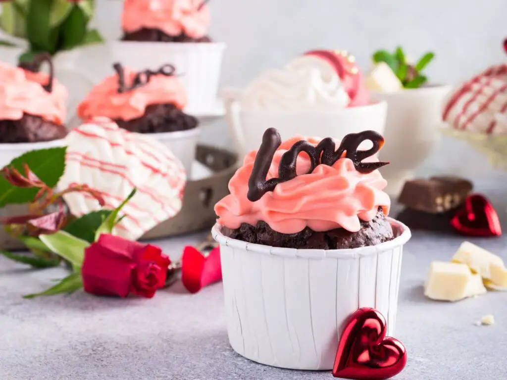 Cupcake coberto com merengue, decorado com a palavra "love" escrita em chocolate.