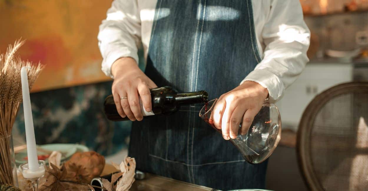 Vinho tinto sendo cuidadosamente vertido em um decanter de vidro.