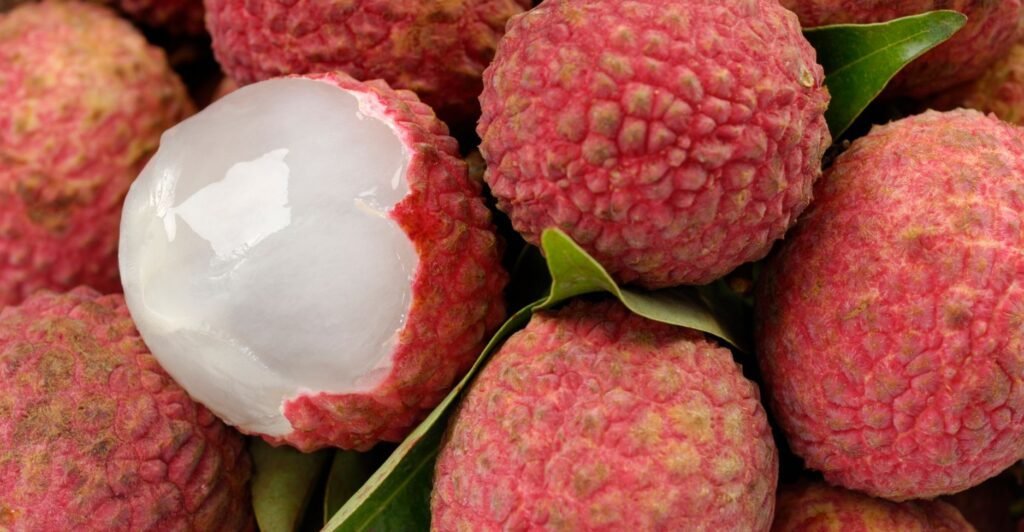 frutas de lichia expostas em uma mesa. uma lichia esta descascada.