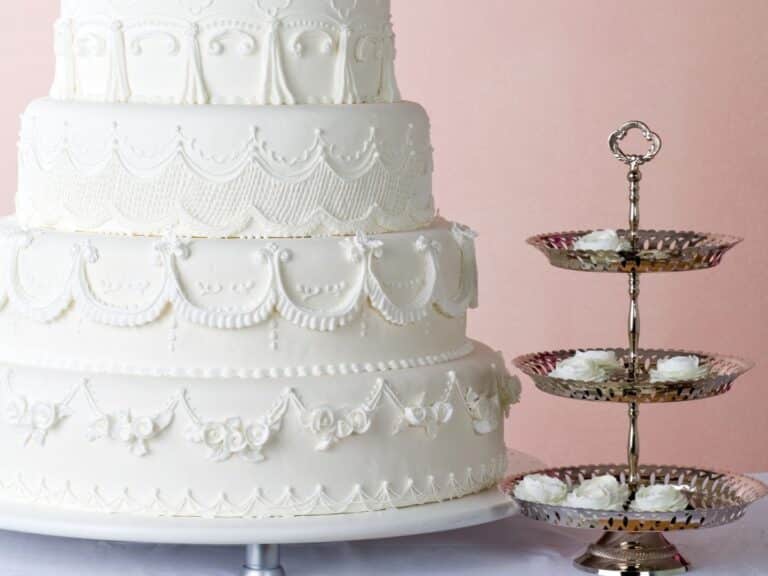 Bolo de casamento de cinco andares, decorado com glacê real detalhado em padrões elegantes.