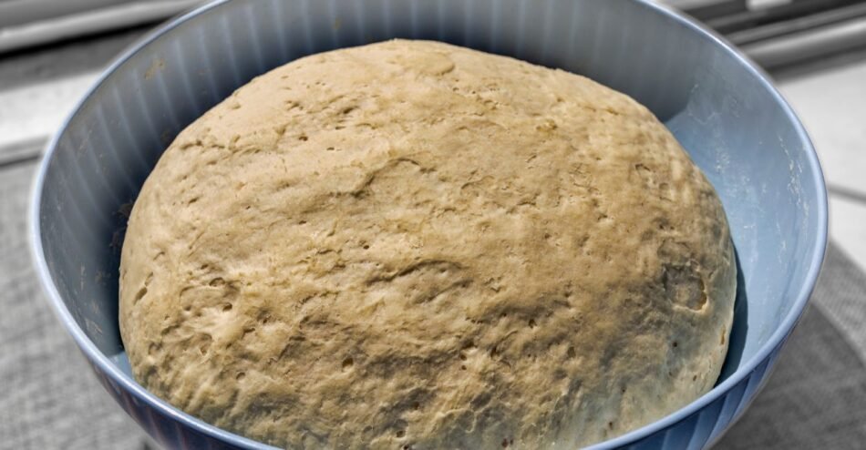 Massa de pão crescendo em tigela coberta com pano, durante o processo de levedação.