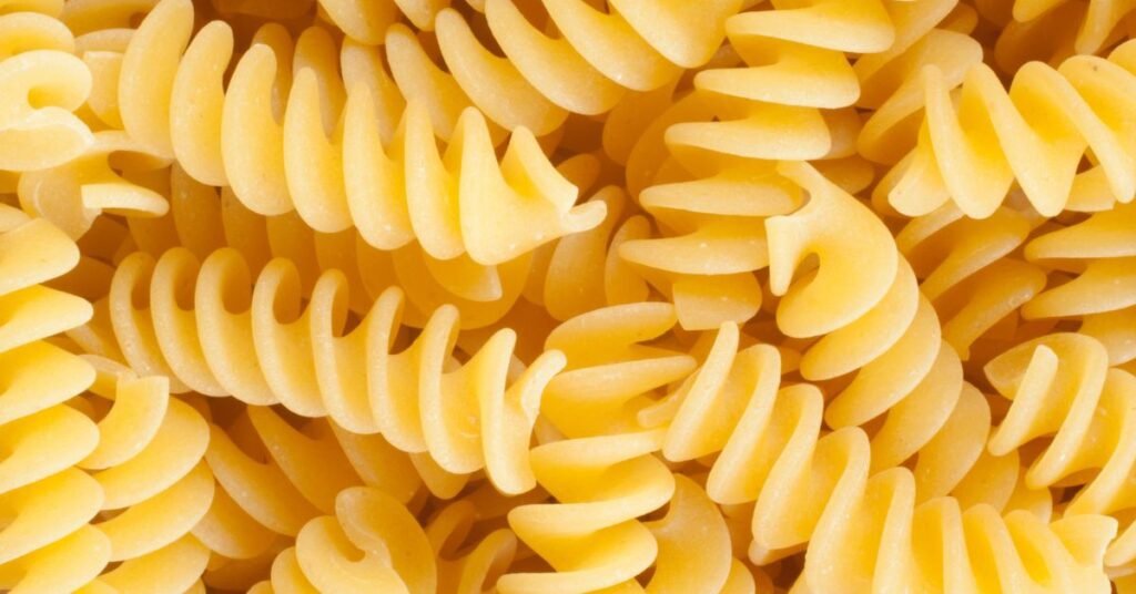 Macarrão fusilli cru, também chamado de parafuso, tipo de macarrão em espiral mostrado em tela cheia.