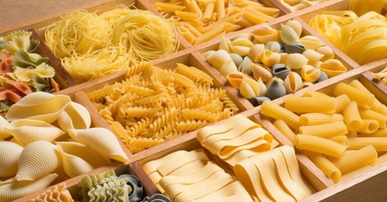 Mesa com vários tipos de macarrão nomes e formatos da massa italiana.