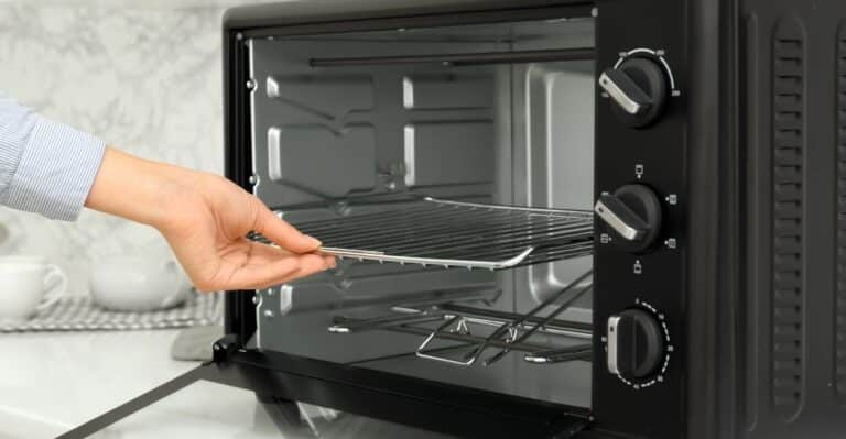 mulher retirando as grades deslizantes do melhor forno elétrico do ano
