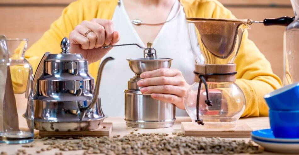 Grãos de café sendo moídos em moedor manual sobre uma bancada.