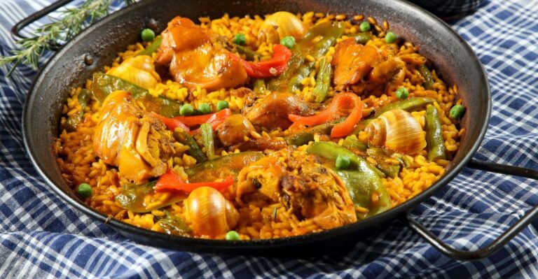 Paella Valenciana tradicional em sua paellera, vista de cima, com frango, legumes e grãos de arroz dourados.