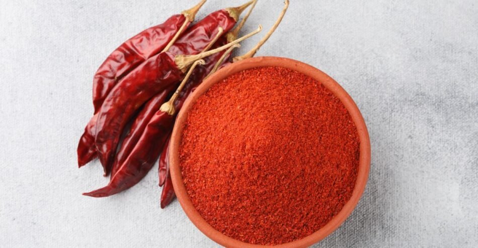 Páprica picante em pó em pote de vidro, destacando cor avermelhada intensa e textura fina, pronta para temperar pratos gourmet.