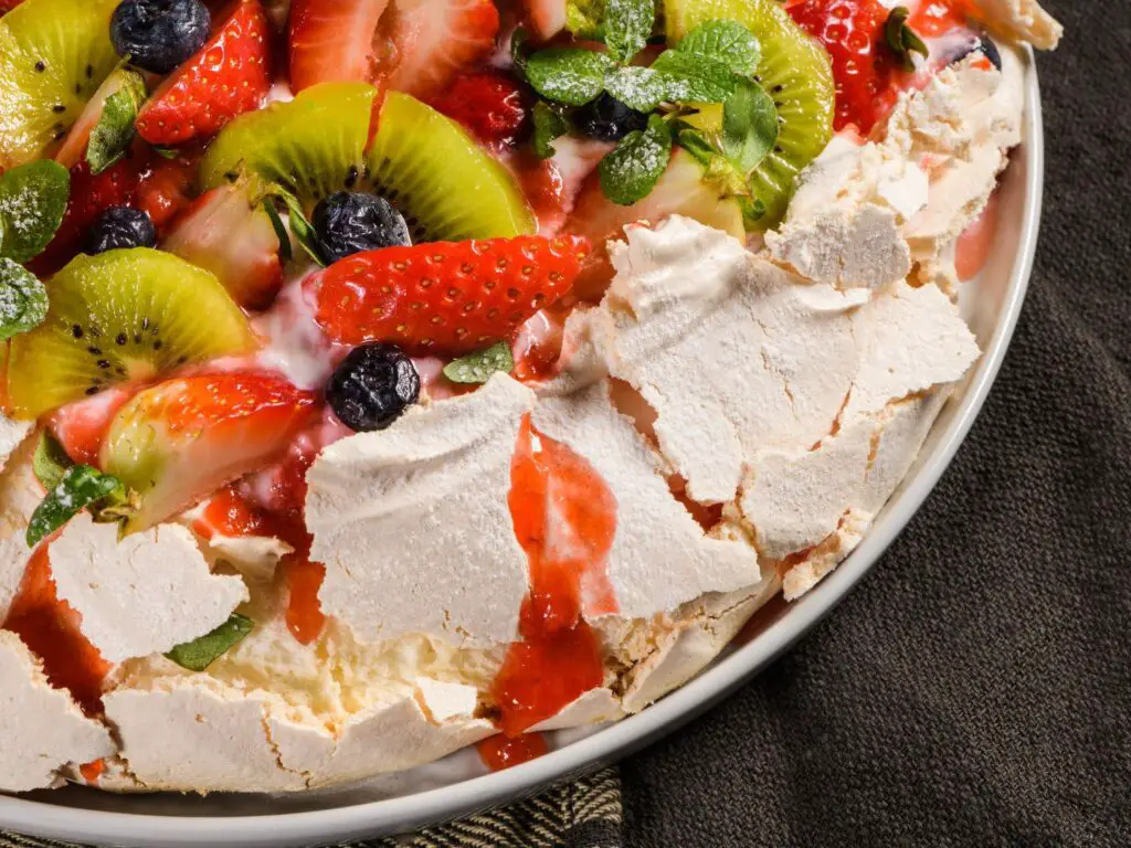 Pavlova com cobertura de frutas frescas e um merengue crocante e leve.