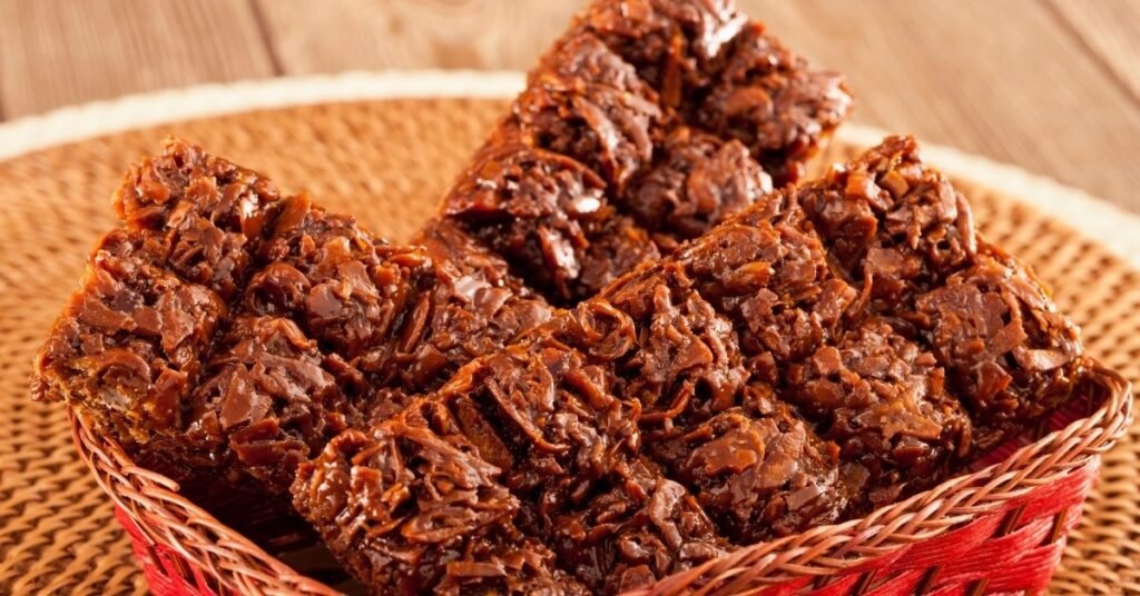 Pedaços de quebra-queixo com coco ralado, servidos em prato decorado, típica comida de festa junina doce.