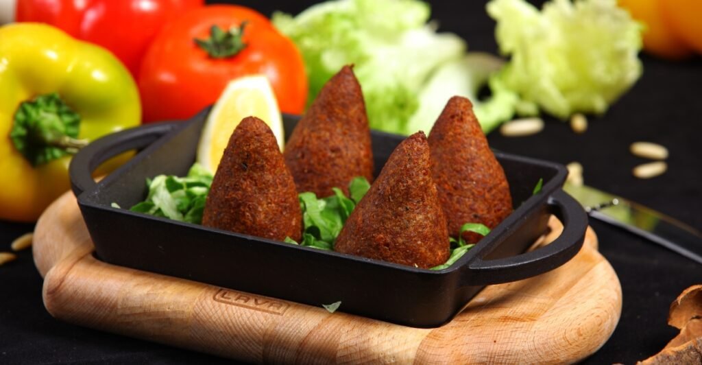 Quibe frito tradicional da culinária árabe servido com limão e hortelã.