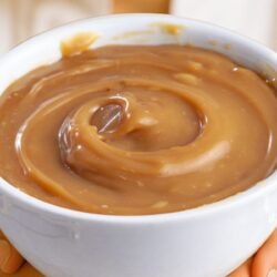 Confeiteira segurando tigela branca de recheio com doce de leite.