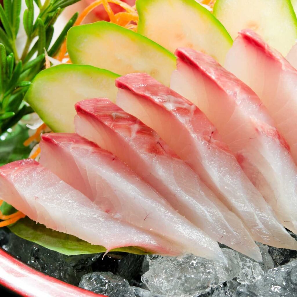 Prato de sashimi de hamachi (olho-de-boi) com fatias frescas e delicadas, acompanhado de wasabi e gengibre.