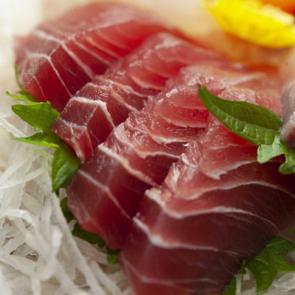 Prato de sashimi de atum (maguro) com fatias frescas e bem cortadas, acompanhado de wasabi e gengibre.